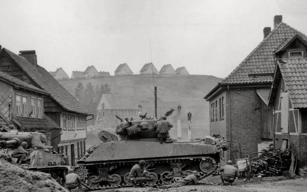 U.S. troops take cover behind their tanks as they look for a sniper, Andreasberg, Germany, 1945