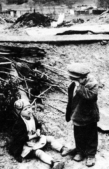 Russian children stand abandoned outside the ruins of their home. Nazi soldiers destroyed their home and took their parents prisoner. [1942) 