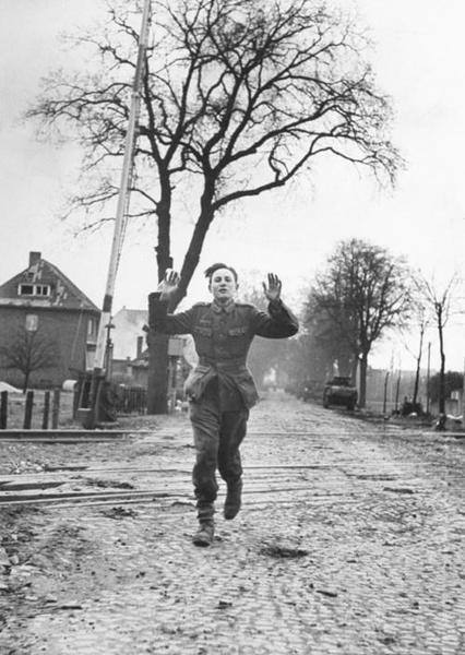 Very young German soldier running with his arms raised in surrender. Lemgo, Germany, 1945