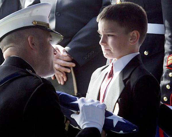 Christian Golczynski, de 8 anos de idade, recebe a bandeira em honra a seu pai, o sargento da Marinha Marc Golczynski, durante uma cerimônia fúnebre